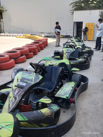 Go-karts lined up at a track with young people preparing to race.