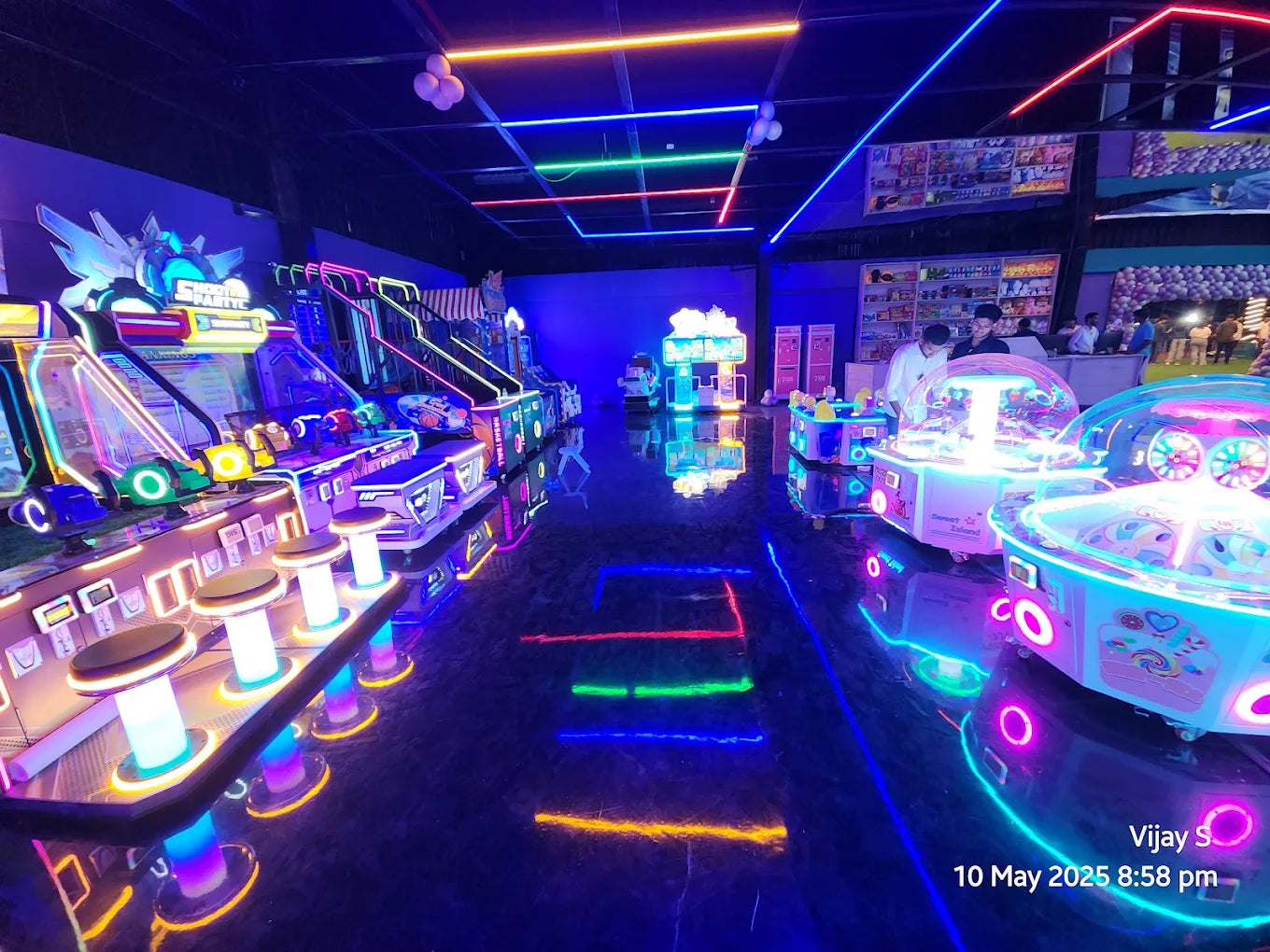 An arcade with neon lights and young adults playing games.