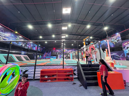 Children and adults enjoy a trampoline park with colorful walls and trampolines.