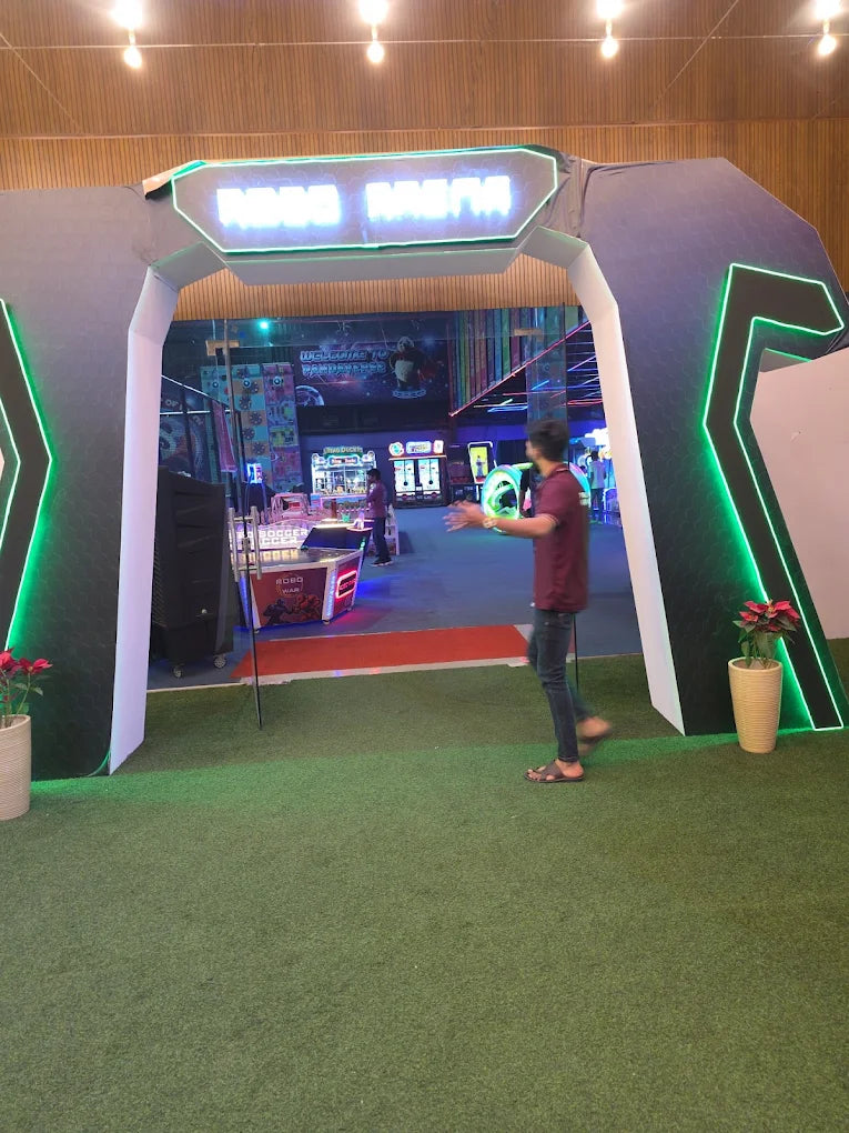 A young man walks through an arcade entrance with neon lights. The arcade appears to be a game center with various machines.