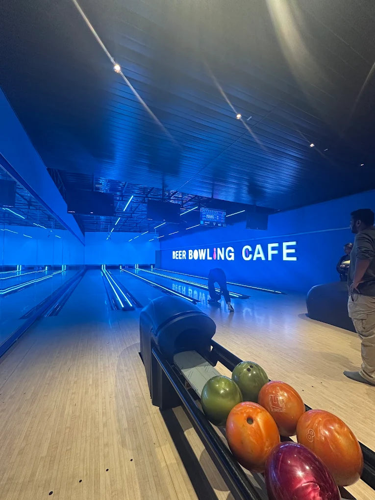Bowling alley with neon lights and bowling balls on the rack.