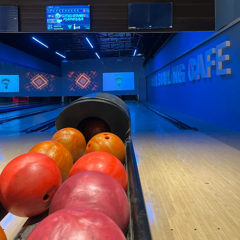 Bowling balls in a lane at a bowling alley with a "Bowling Cafe" sign.