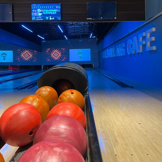 Bowling balls in a lane at a bowling alley with a "Bowling Cafe" sign.