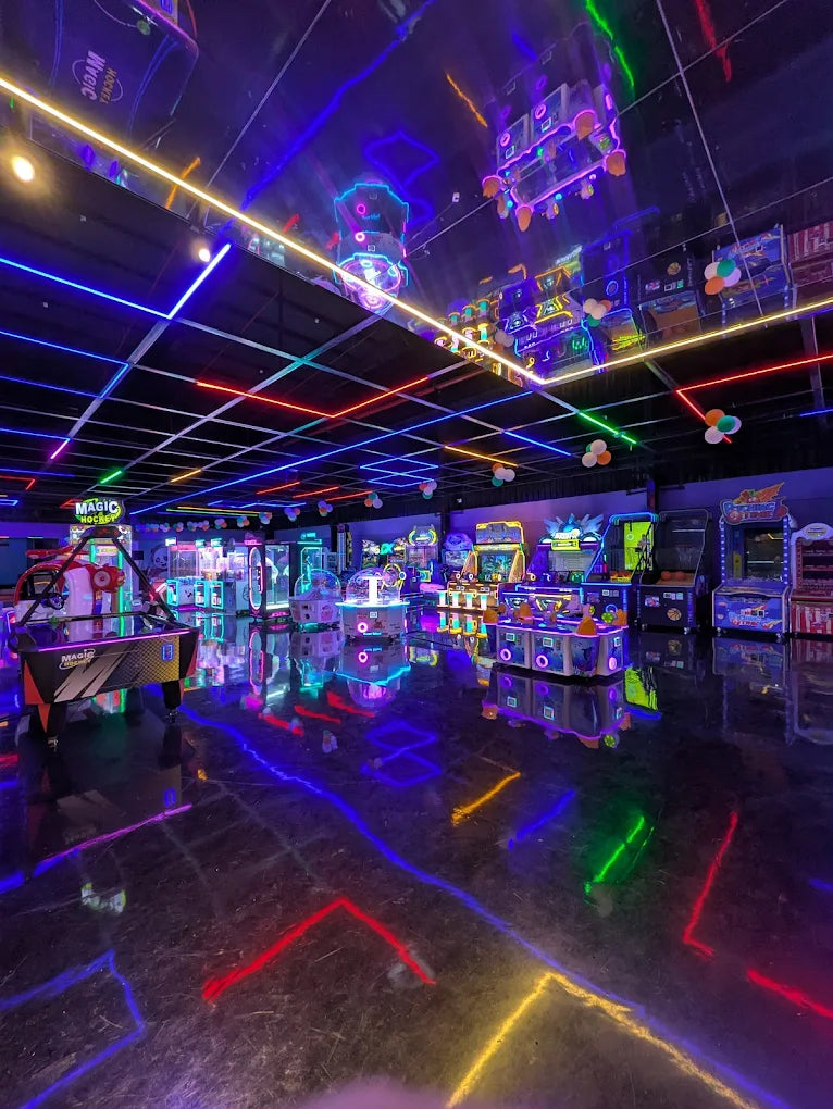 A brightly lit arcade with neon lights and game machines, reflecting on the shiny floor.