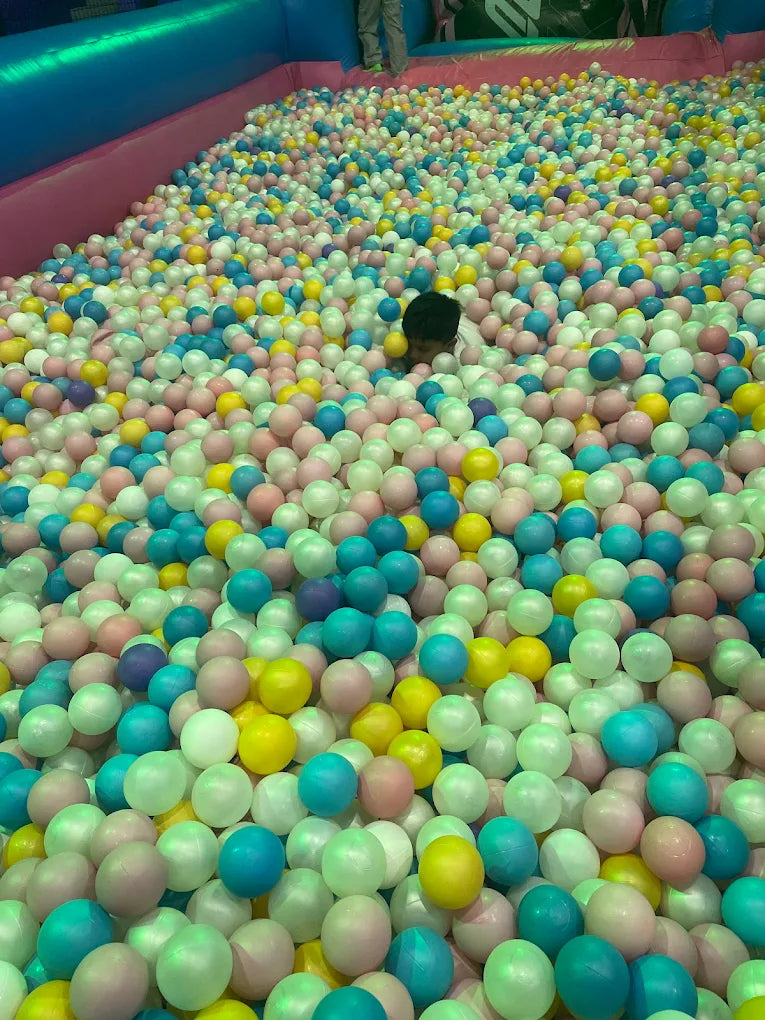 A child plays in a ball pit filled with colorful balls.