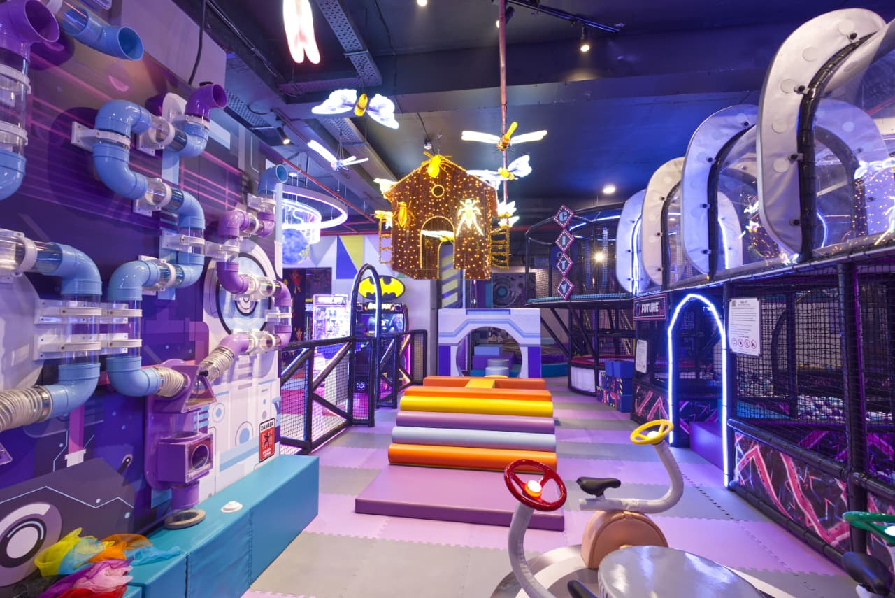 Colorful indoor playground with various equipment and structures.