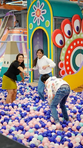 Children play in a ball pit at an indoor playground.