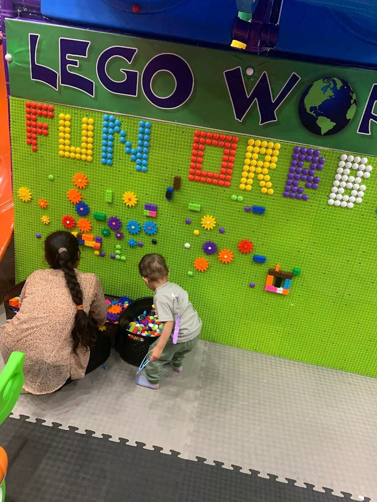 Children creating colorful designs with Lego and gears on a bright green wall at Fun Orbbit Kids Play Area Gujranwala Town