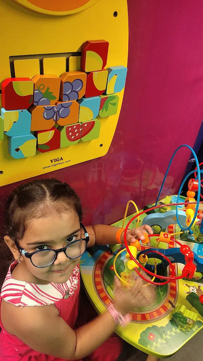 Child with glasses engaged with colorful bead maze and fruit puzzle at Fun Orbbit Kids Play Area Gujranwala Town Delhi