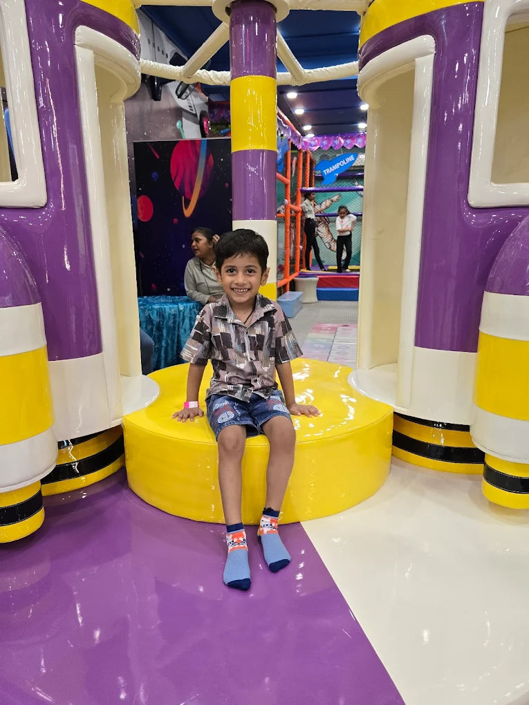 Smiling child sitting on circular yellow platform inside colorful indoor play structure at Fun Orbbit Gujranwala Town Delhi
