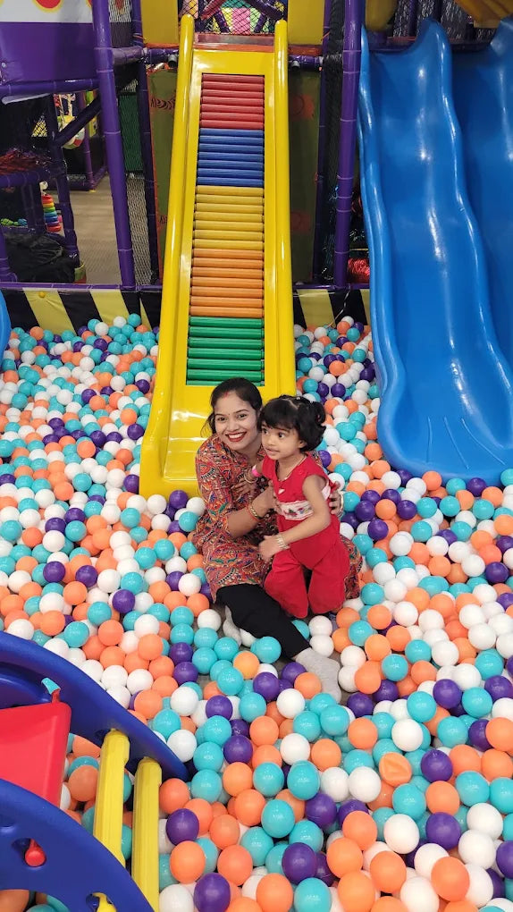 Woman and child sitting in colorful ball pit near yellow slide inside Fun Orbbit Kids Play Area Gujranwala Town Delhi