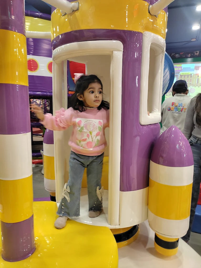 Child playing on a colorful playground structure with purple and yellow accents.