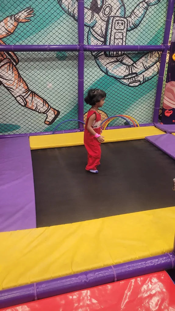 Toddler in red outfit jumping on indoor trampoline with colorful padded edges at Fun Orbbit Kids Play Area Gujranwala Town Delhi
