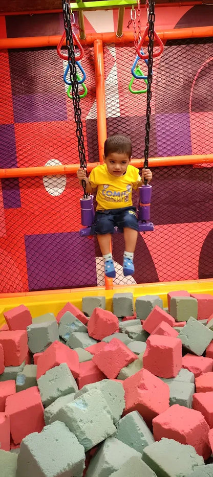 Young child swinging over foam pit with red and gray blocks against colorful play area background at Fun Orbbit Gujranwala Town Delhi