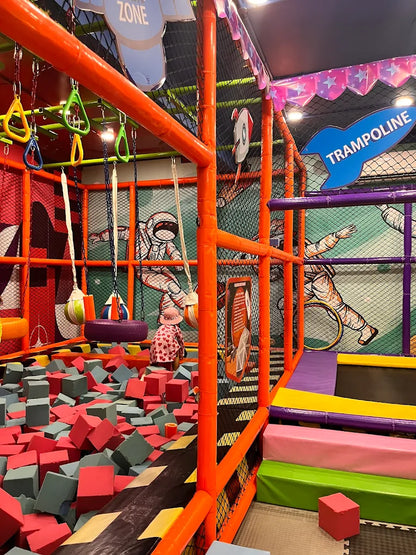 Colorful indoor play area with foam pit, hanging swings, and trampoline section featuring space-themed wall art at Gujranwala Town Delhi