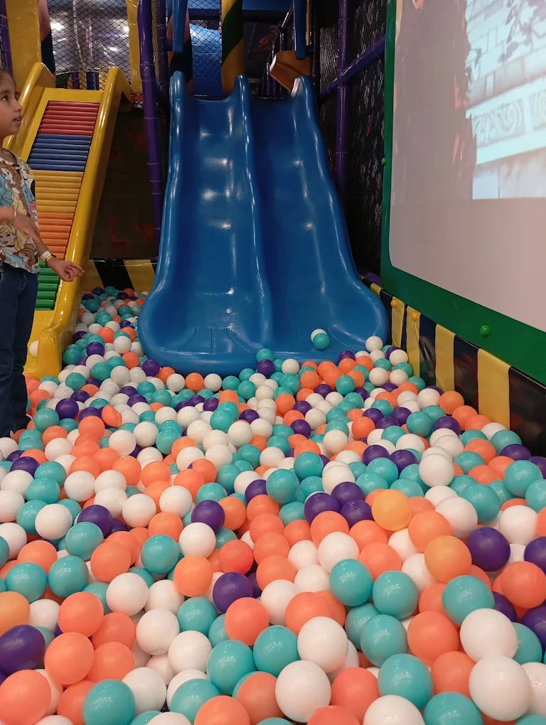 Child standing near dual blue slides leading into colorful ball pit at Fun Orbbit Kids Play Area Gujranwala Town Delhi