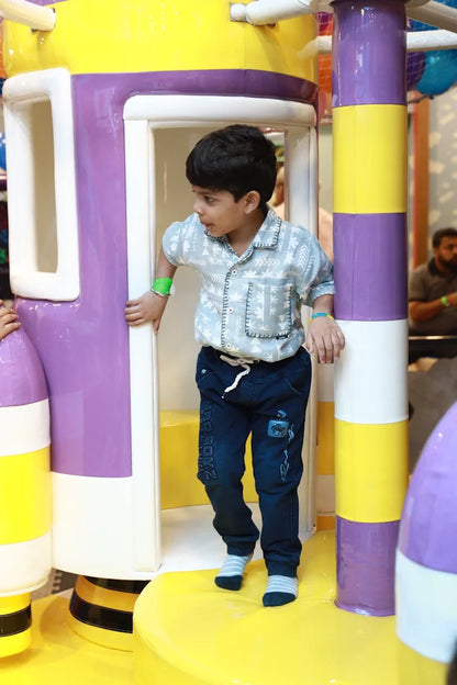 Boy wearing patterned shirt and dark pants playing inside yellow and purple play structure at Fun Orbbit Kids Play Area Gujranwala Town Delhi