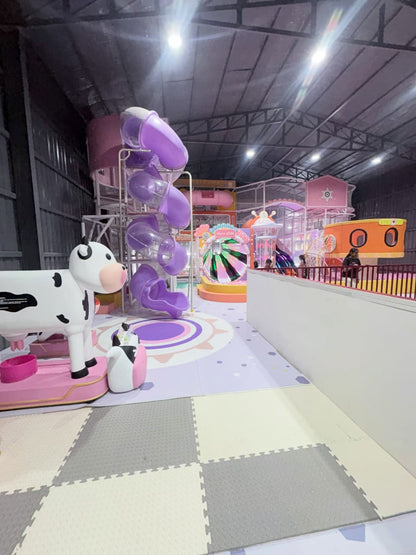 A colorful indoor playground with purple slides and a cow-themed play area for children.