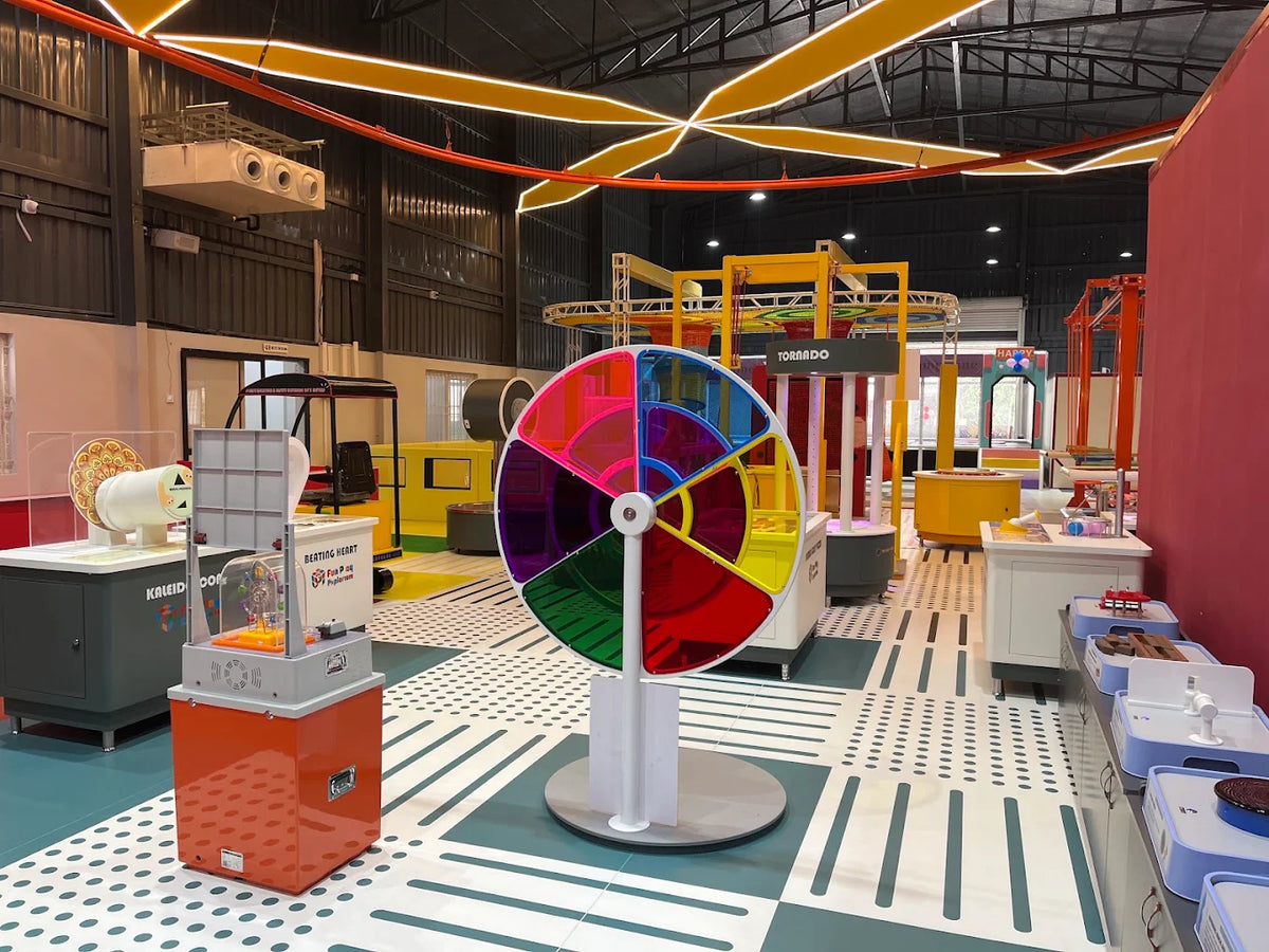 A colorful science museum exhibit with interactive displays and a large spinning wheel.