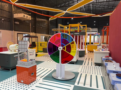 A colorful science museum exhibit with interactive displays and a large spinning wheel.