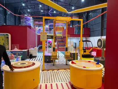 An indoor children's play area with colorful interactive exhibits and a yellow overhead pulley system.