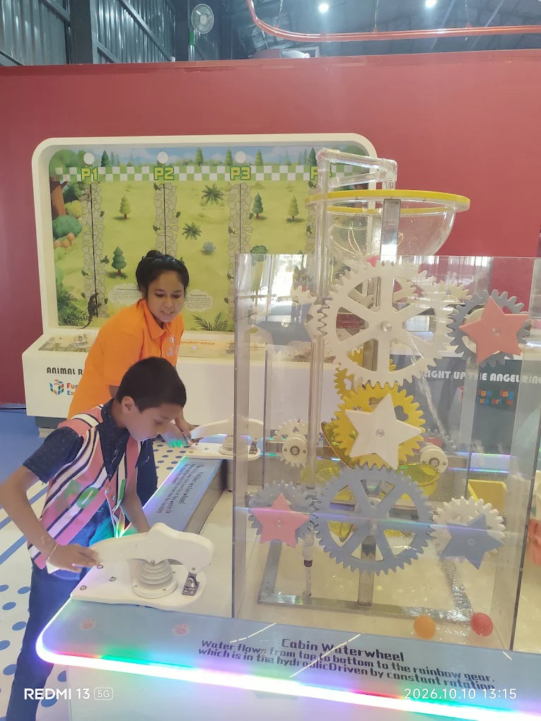 Children interact with a water wheel exhibit featuring gears and a colorful display.
