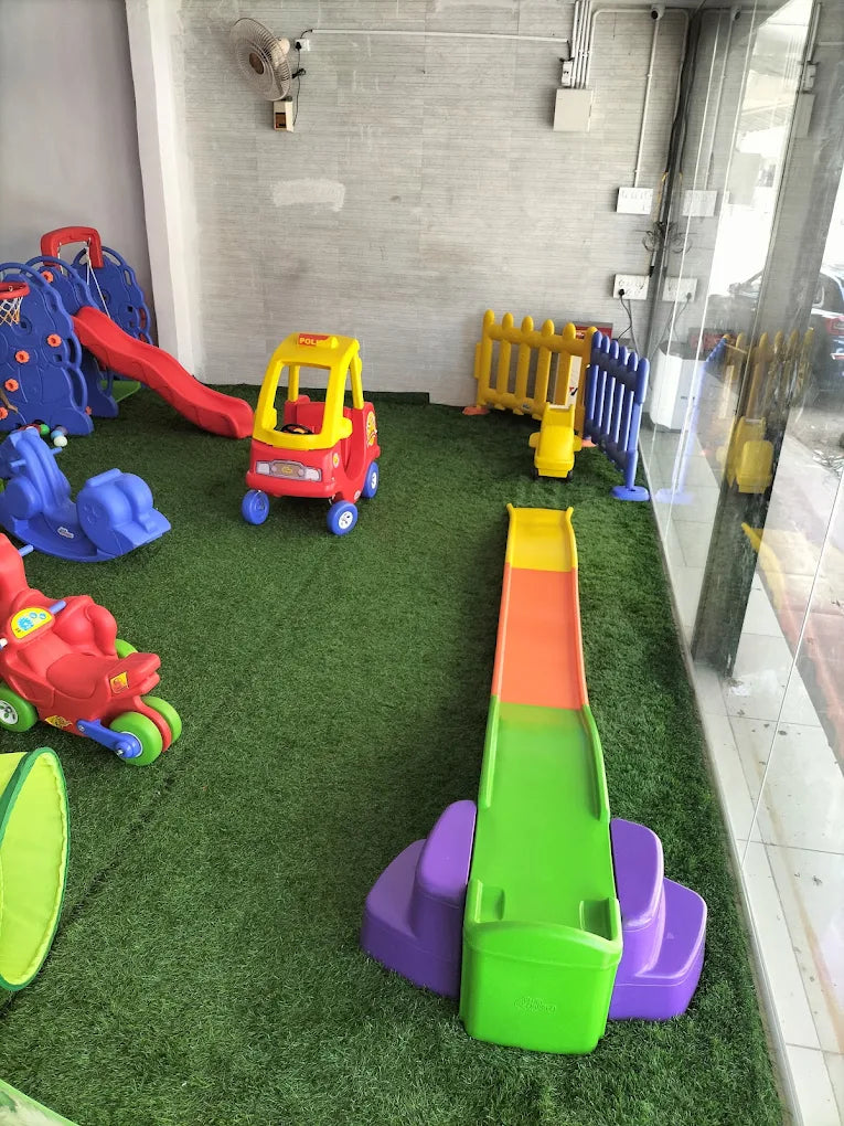 A colorful indoor playground with slides, a toy car, and a basketball hoop for young children.