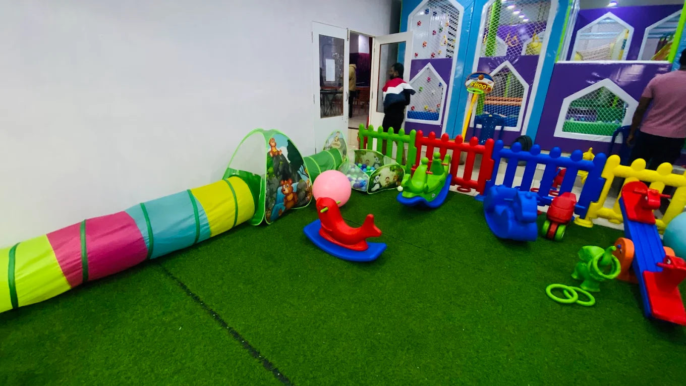 A colorful indoor playground with soft toys and a ball pit for children.