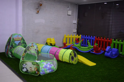 A colorful indoor play area for young children with tunnels, a ball pit, and rocking toys.