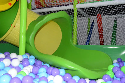 A colorful ball pit with a green slide in a children's play area.