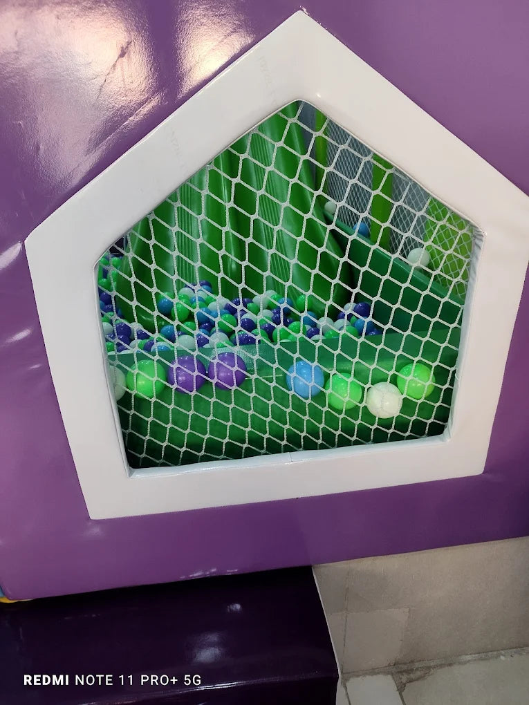 A ball pit filled with colorful balls is visible through a pentagonal window in a purple play structure.