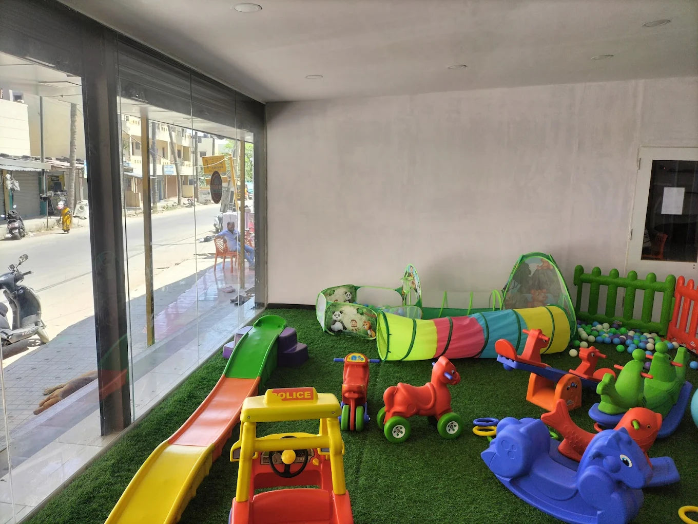 Indoor play area for young children with slides, tunnels, and rocking toys.