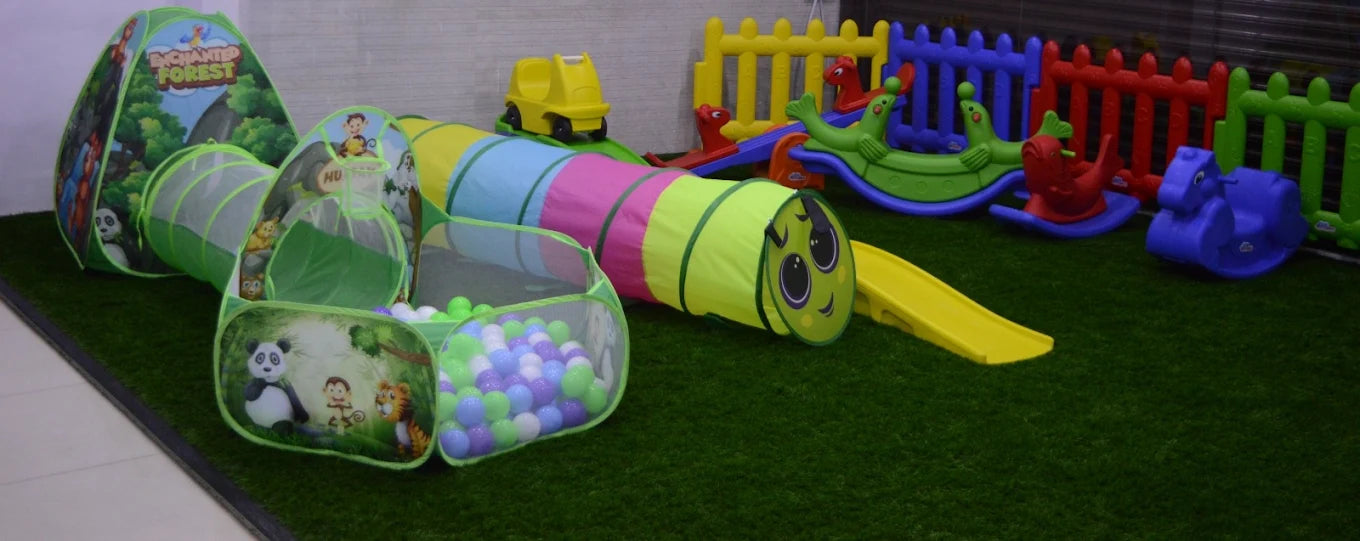 A colorful indoor play area for young children with tunnels, a ball pit, and rocking toys.