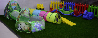 A colorful indoor play area for young children with tunnels, a ball pit, and rocking toys.