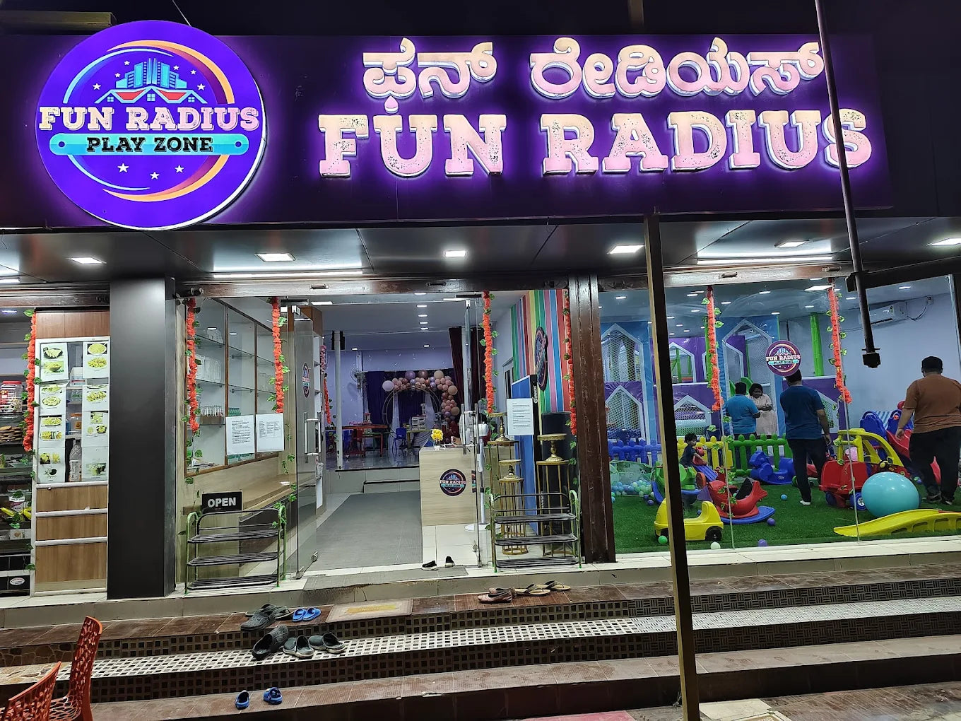 A brightly lit indoor play zone for children, with colorful slides and play structures, is visible through the glass storefront.