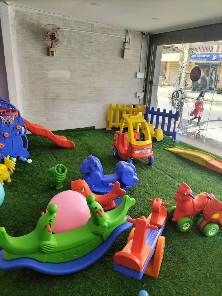 A colorful indoor playground with various toddler toys and a child playing.