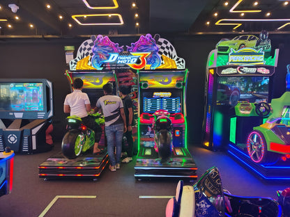 Young adults play motorcycle racing arcade games in a brightly lit entertainment center.
