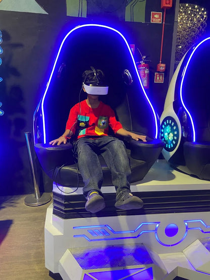 A young person in a VR headset sits in a futuristic chair with blue neon lights.