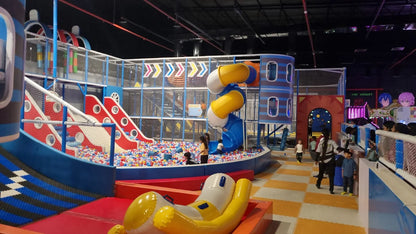 Children play in a colorful indoor playground with slides and a ball pit.