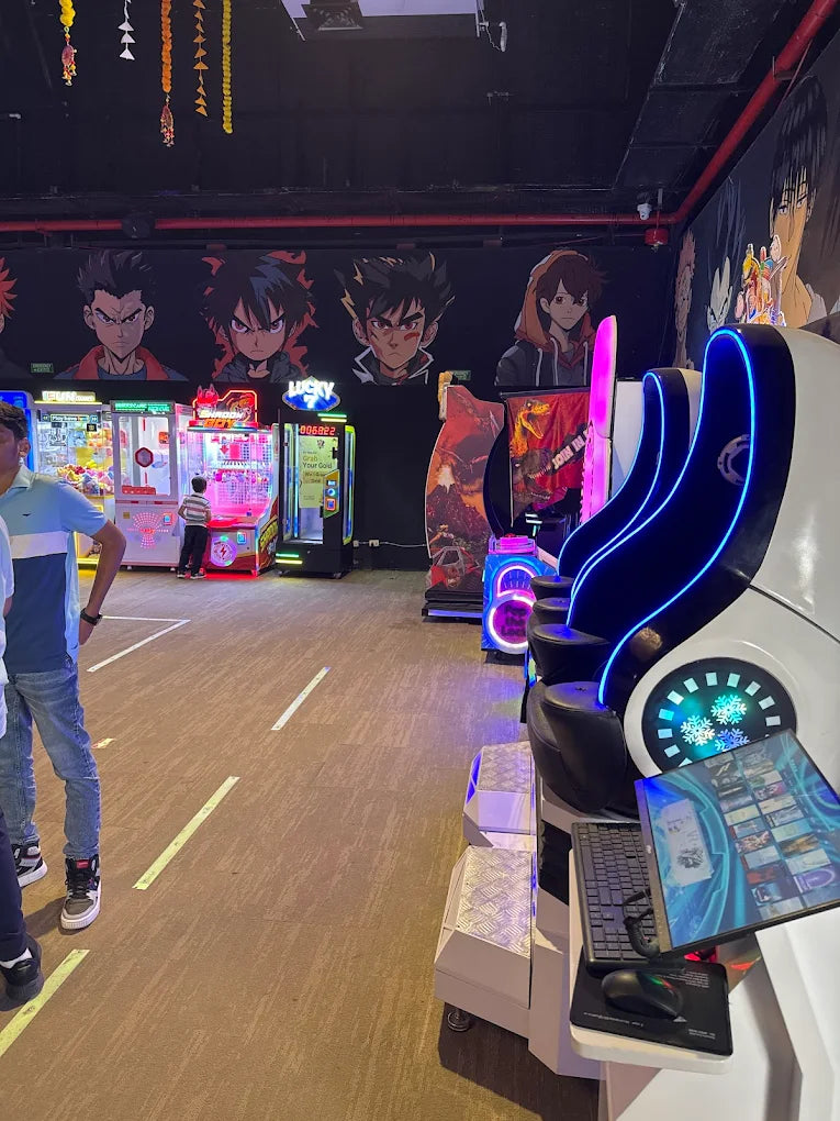 An arcade with anime-themed decor and various game machines, including a racing simulator, with young people playing.