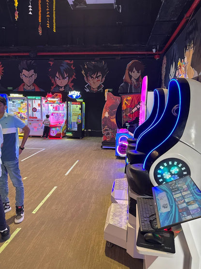An arcade with anime-themed decor and various game machines, including a racing simulator, with young people playing.