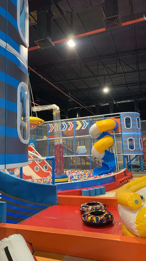 A colorful indoor playground with slides, a ball pit, and play structures for children.