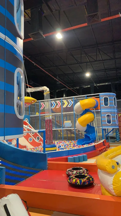 A colorful indoor playground with slides, a ball pit, and play structures for children.