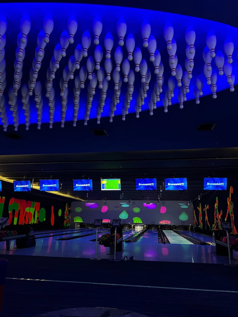 Bowling alley with bowling pins hanging from the ceiling and neon lights.