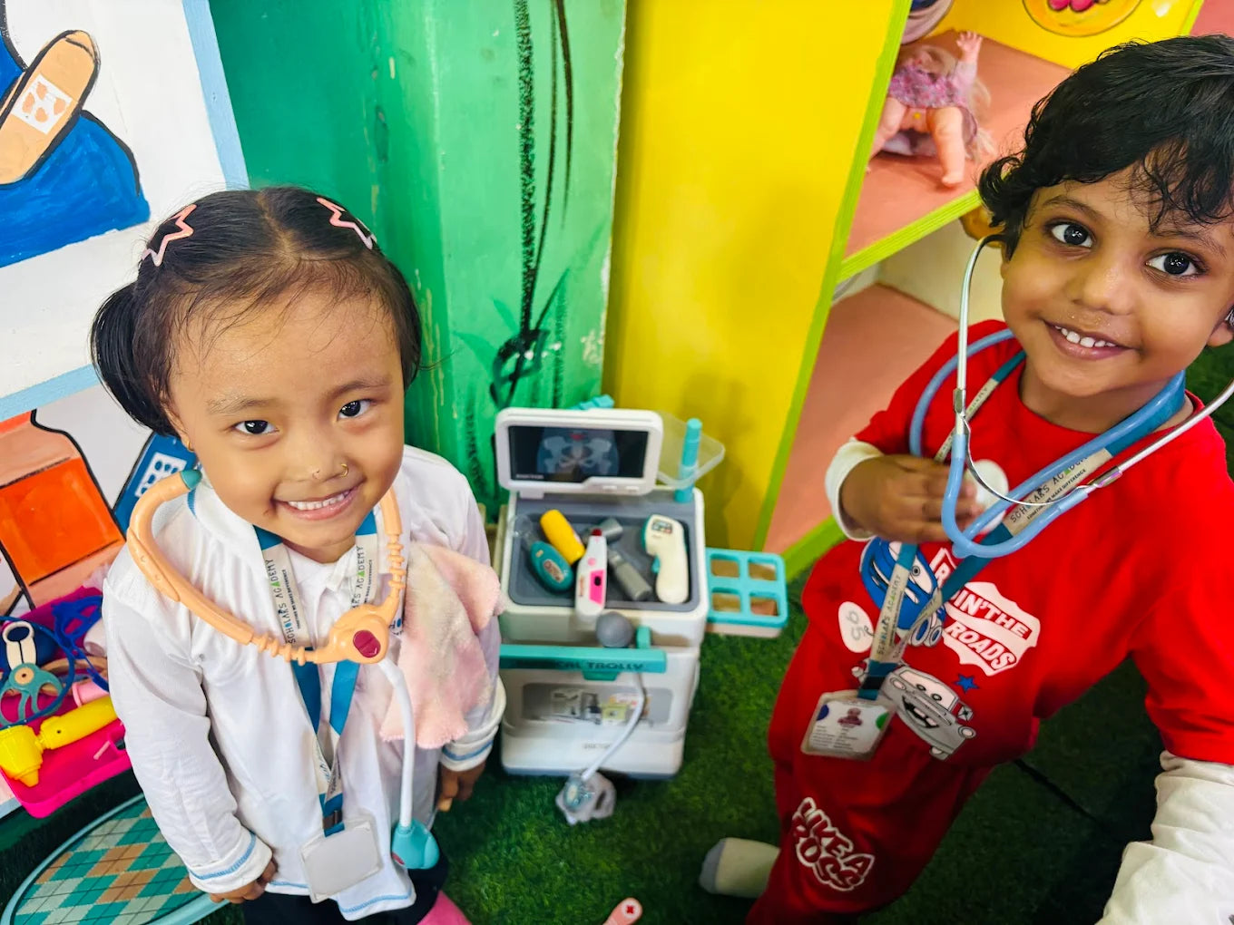 Two young children dressed as doctors play with a toy medical kit.