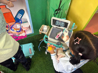 A young child plays with a toy doctor's kit, examining a toy X-ray.