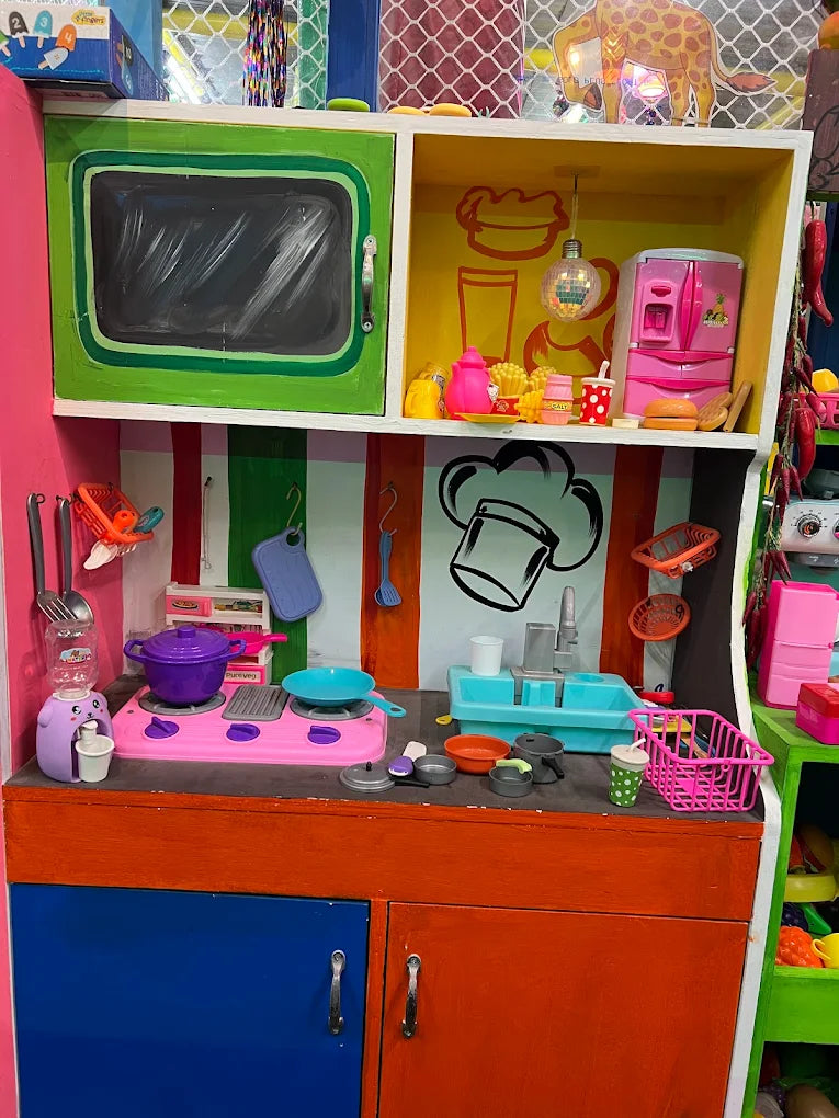 A colorful toy kitchen with miniature appliances and food items, set up for imaginative play.