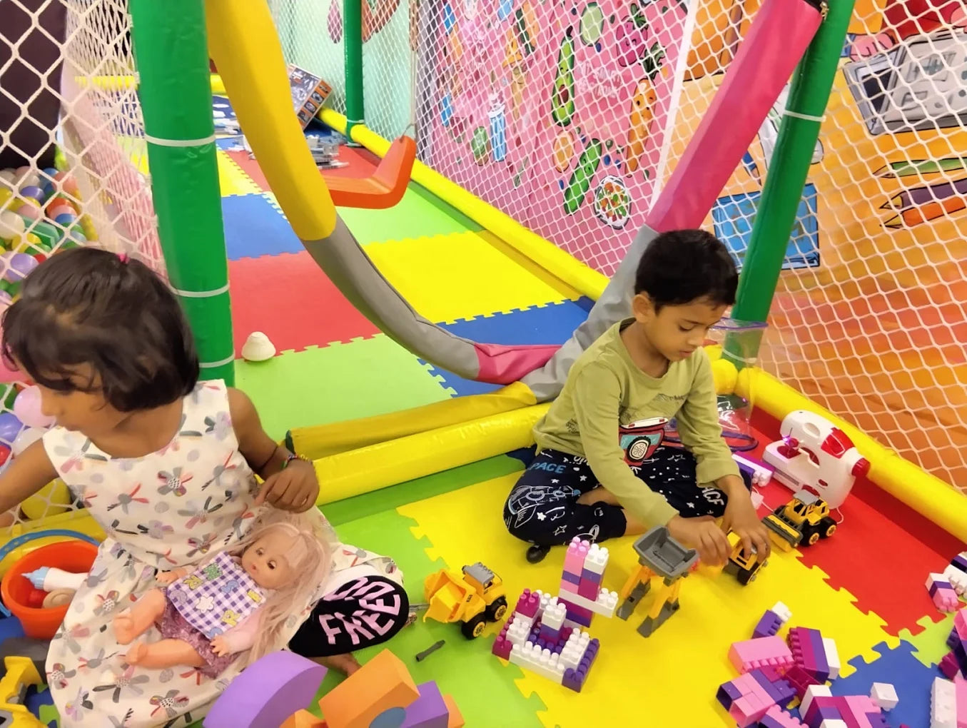 Two young children play with toys in a colorful indoor playground.