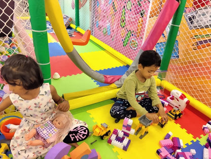 Two young children play with toys in a colorful indoor playground.