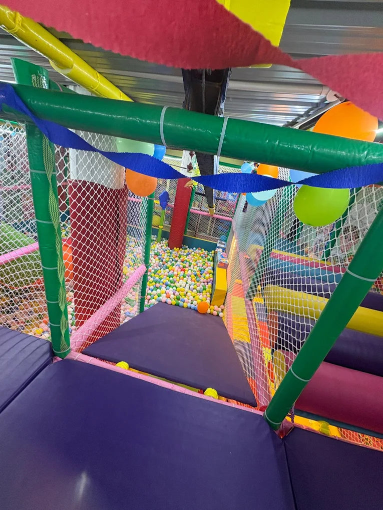 A colorful indoor playground with a ball pit and soft play structures for children.